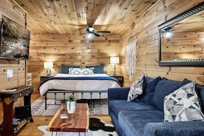 Relax in this inviting room with a neatly made bed, comfortable sofa, and potted plant.