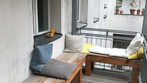 A wooden bench with cushions, a small table, and a window with a view of the building's interior.