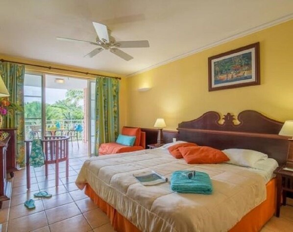 Relax in this serene retreat with a large bed, ceiling fan, and sliding glass door leading to an outdoor area.
