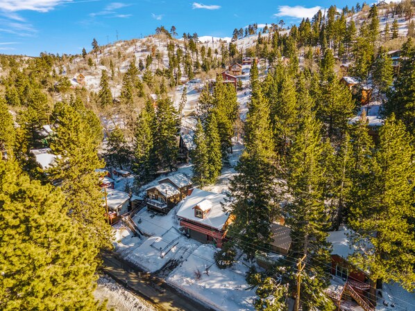 Un pueblo en la montaña cubierto de nieve, con cabañas de madera y un telesilla.
