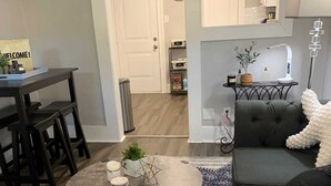 Ein modernes Wohnzimmer mit einem runden Couchtisch, einem grauen Sofa und einem dunkel gemusterten Teppich.