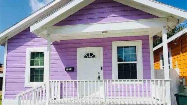 Ein zweistöckiges Haus mit violetten Wänden und weißen Verzierungen.