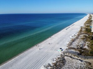 An aerial view of a beach with a long stretch of sand, a clear blue ocean, and a few people walking. - AV33 - Lovely Oceanfront 2-Bedroom Condo with Pool (Fort Walton Beach)