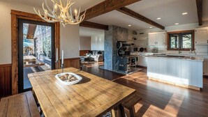Une cuisine spacieuse dotée d’un îlot central, de poutres en bois et d’un mur d’accent en pierre.