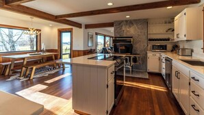 Une cuisine moderne avec un mur recouvert de pierres apparentes, des poutres en bois et un grand îlot central.