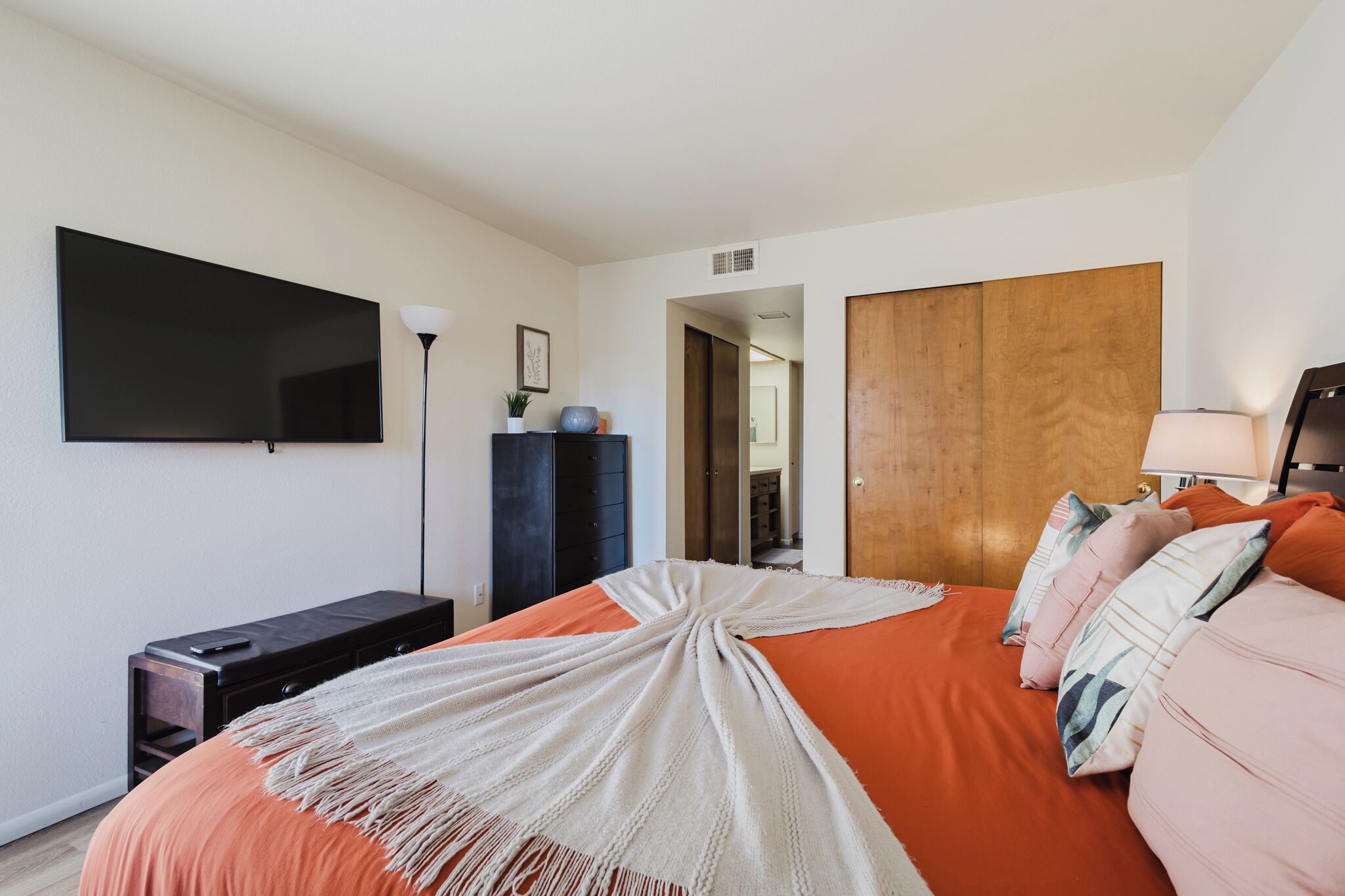 A bedroom with a bed, a TV, a dresser, and a wardrobe.