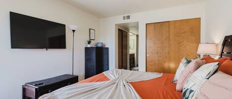 A bedroom with a bed, a TV, a dresser, and a wardrobe.