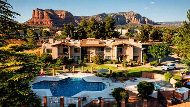 A hotel with a swimming pool, surrounded by lush greenery and mountains in the background. - Tennis & Pickle ball courts, Golf, Hiking (Sedona)