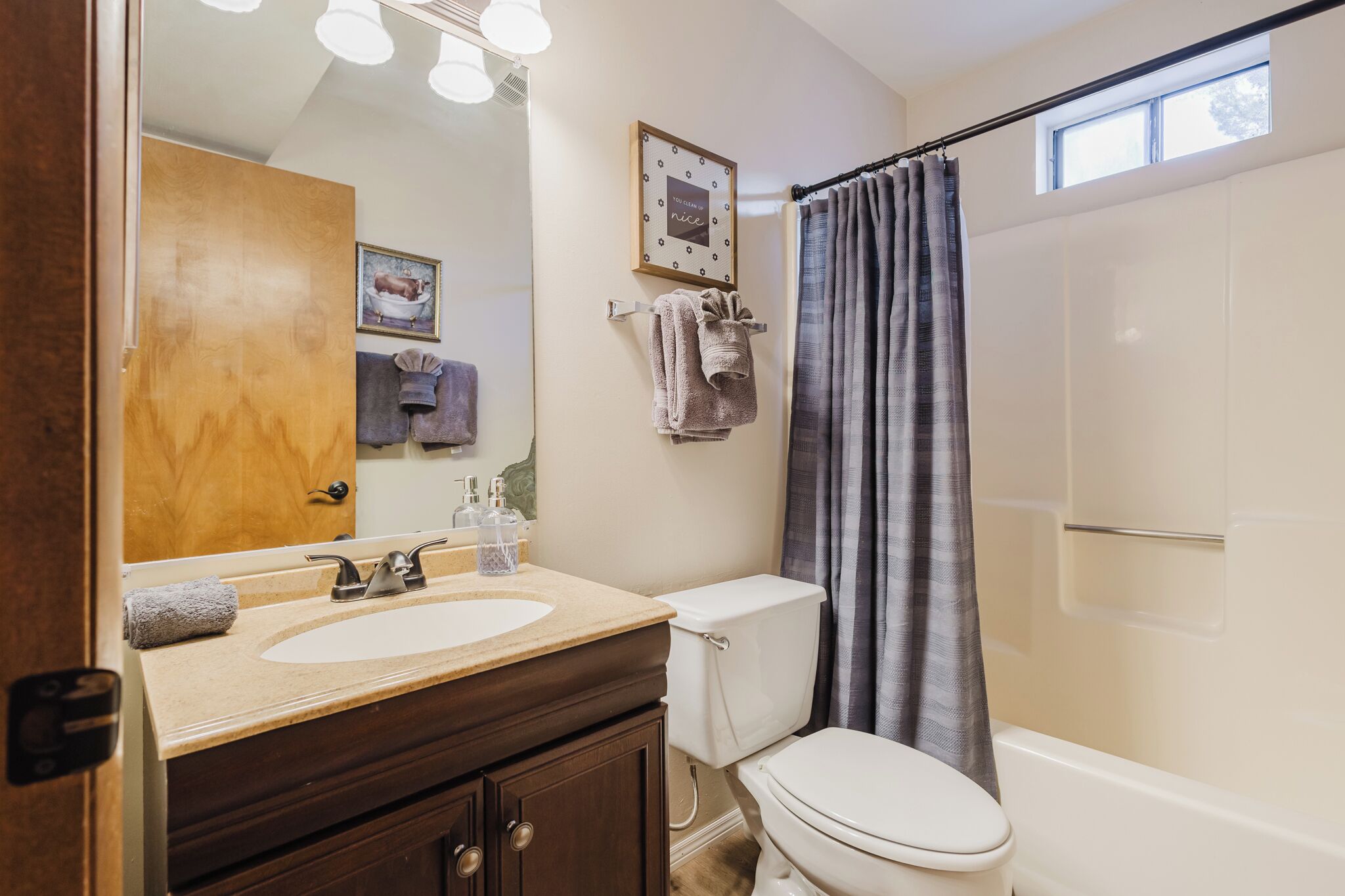 Une salle de bain équipée d’un lavabo, de toilettes et d’une douche. On y trouve un porte-serviettes avec des serviettes et un tableau encadré accroché au mur.