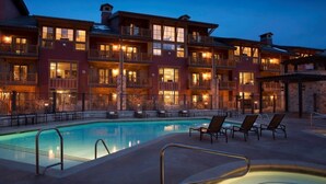 Un hotel con piscina, mobiliario exterior y varios balcones.