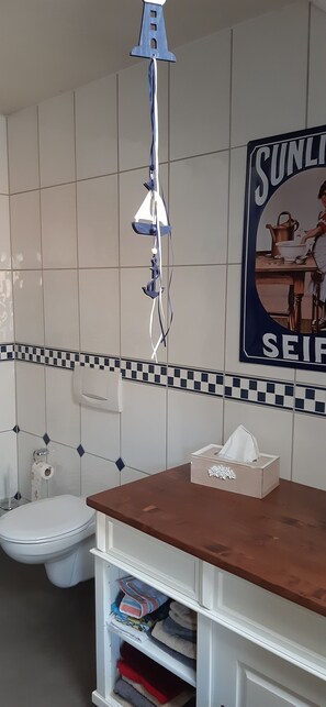 A bathroom with a toilet, a sink with a tissue box, and a towel rack.