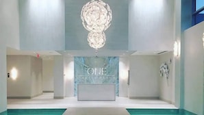 Rebedor modern d'un hotel amb una recepció, un llum candelabrum gran i una zona de piscina.