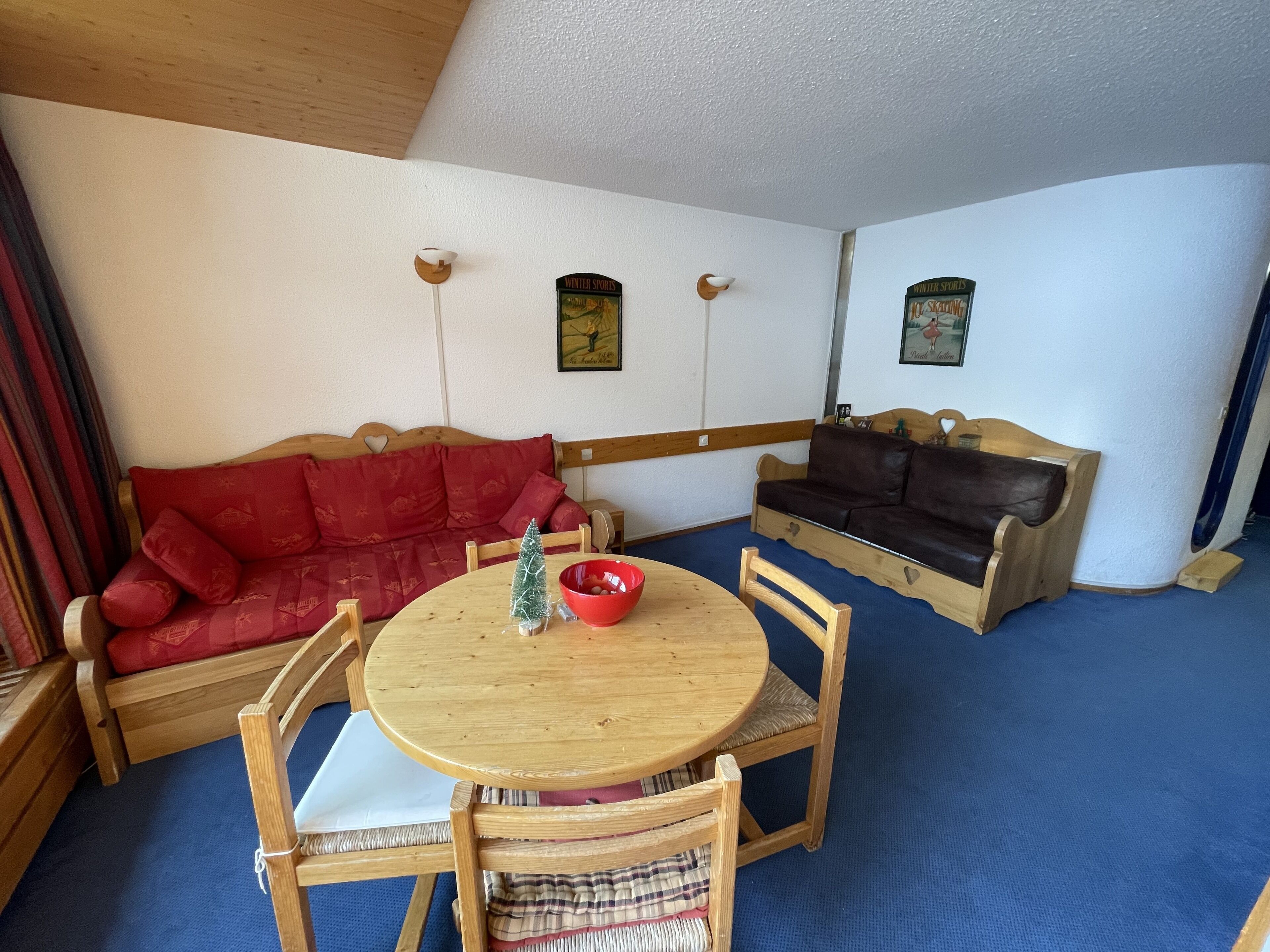 Ein gemütliches Zimmer mit einem Holztisch, zwei Sofas und einer kleinen Weihnachtstanne.
