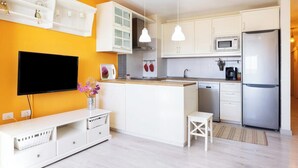 A modern kitchen with white cabinets, a built-in microwave, and a stainless steel refrigerator.