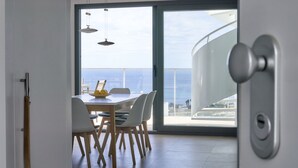A modern dining area with a view of the sea, a wooden dining table, white chairs, and pendant lights. - Penthouse with luxury amenities, a rooftop terrace, and breathtaking views (Manilva)