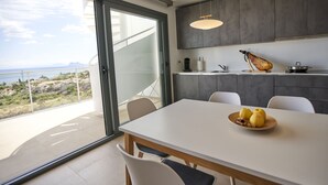 A modern kitchen with a large island, a dining area with a table and chairs, and a view of the ocean through a sliding glass door. - Penthouse with luxury amenities, a rooftop terrace, and breathtaking views (Manilva)