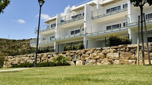A multi-story building with balconies, a stone retaining wall, and a clear sky. - Penthouse with luxury amenities, a rooftop terrace, and breathtaking views (Manilva)