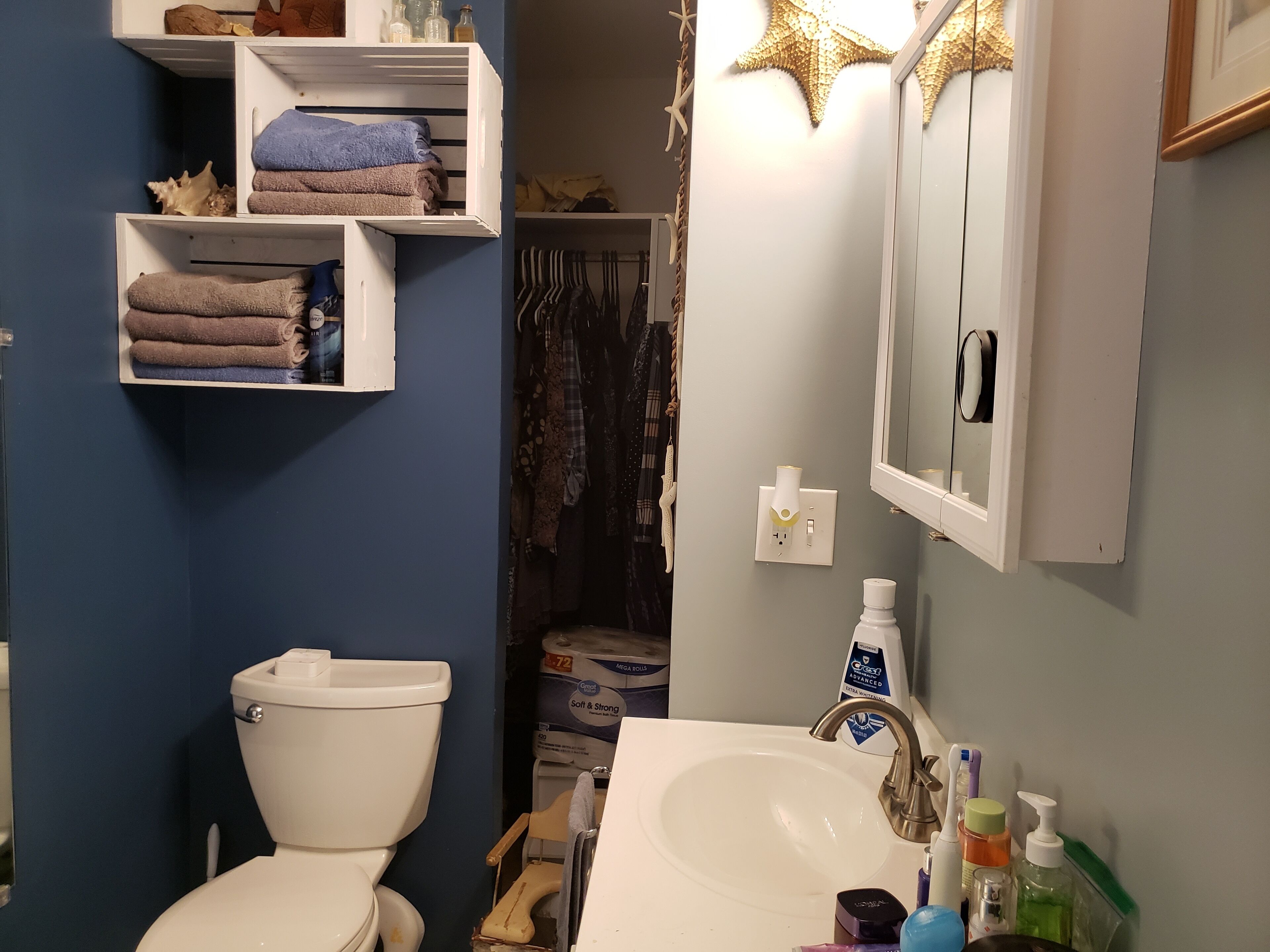 Un baño con inodoro, lavabo y repisas con toallas.