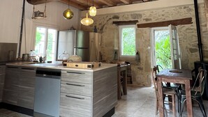 A spacious kitchen with a wooden ceiling, a large island, and a dining area with a view of greenery. - COUNTRY HOME (Castelnau-sur-Gupie)
