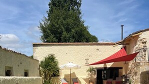 A swimming pool with clear water, surrounded by a building with a stone facade and a red awning. - COUNTRY HOME (Castelnau-sur-Gupie)