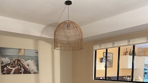 A bedroom with a bed, a dresser, a lamp, a painting, and a window with bottles and a teapot.