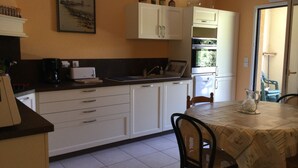 A kitchen with white cabinets, a dining table with chairs, and a window with a view of greenery.