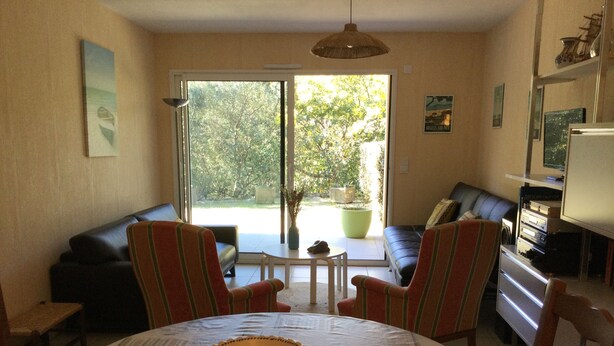 A living room with a dining table, two striped armchairs, a sofa, and a television.