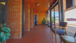 Um espaço coberto ao ar livre, com paredes de tijolo, teto de madeira e chão de azulejos.