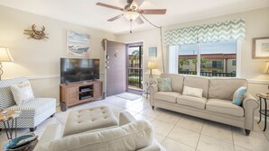 A living room with a ceiling fan, a television, a sofa, and a chair. - Island getaway 3 minutes from sandy beaches. (Treasure Island)