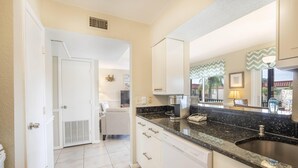 A modern kitchen with white cabinets, a granite countertop, and a stainless steel sink. - Island getaway 3 minutes from sandy beaches. (Treasure Island)