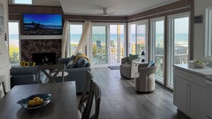 Un salon spacieux doté d’une grande télévision, d’une cheminée et offrant une vue sur l’océan.