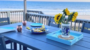 Une table recouverte d’une nappe bleue, un vase rempli de tournesols, une assiette avec de la nourriture et une tasse.