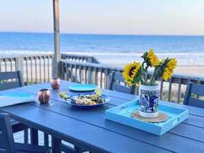 A table with a blue tablecloth, a vase with sunflowers, a plate with food, and a cup.