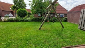 Une cour arrière avec une balançoire, une clôture en bois et une maison en briques en arrière-plan.