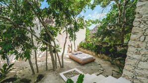 A stone wall, a bed, and a staircase in a garden setting. - Wakax Hacienda - Cenote & Boutique Hotel - Small Luxury Hotels of the World (Tulum)