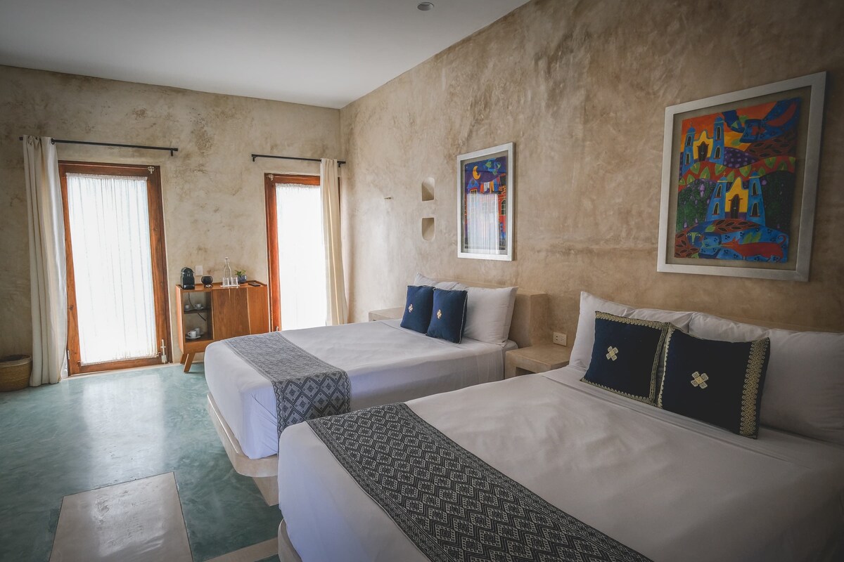 Una habitación de hotel con dos camas, un armario, un escritorio y un cuadro en la pared.