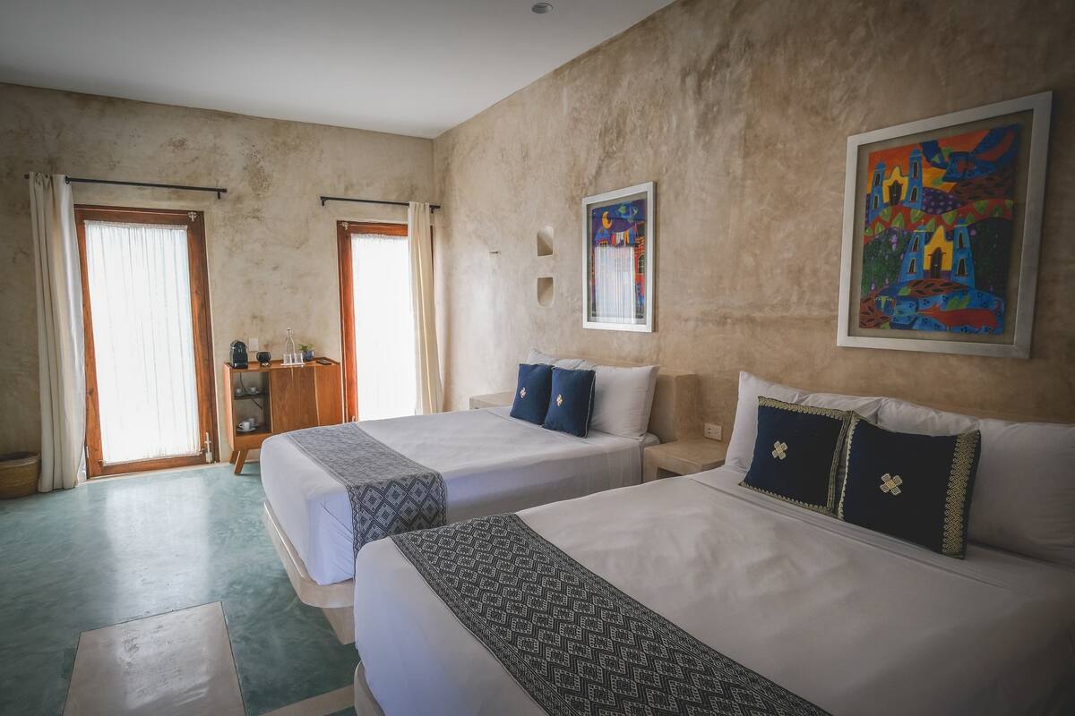 A hotel room with two beds, a wardrobe, a desk, and a painting on the wall.