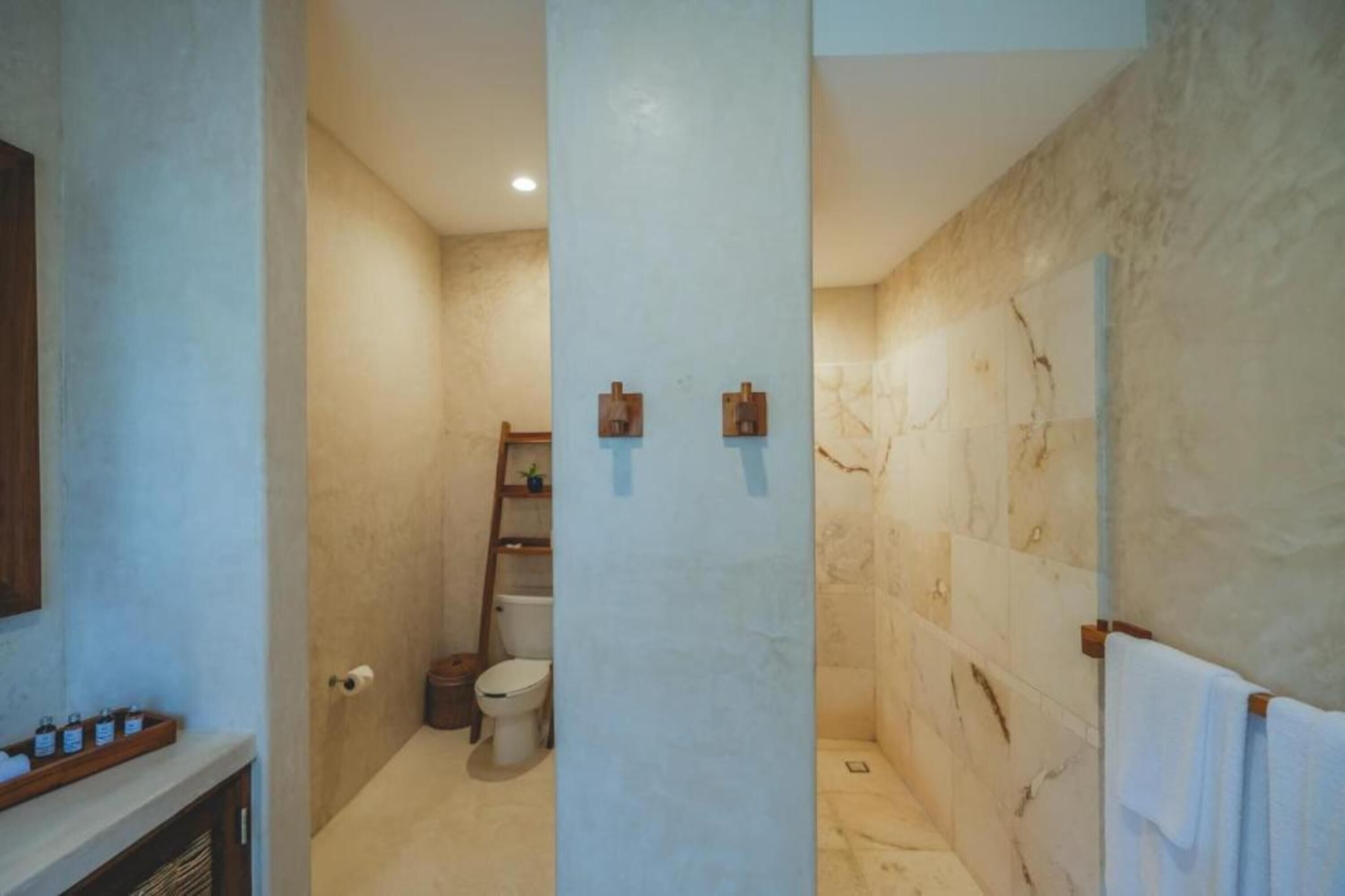 Un baño con pared de mármol, inodoro, lavamanos y perchero.