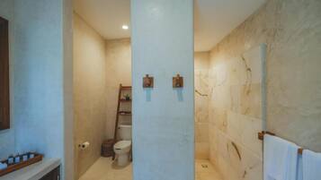Un baño con pared de mármol, inodoro, lavamanos y perchero.