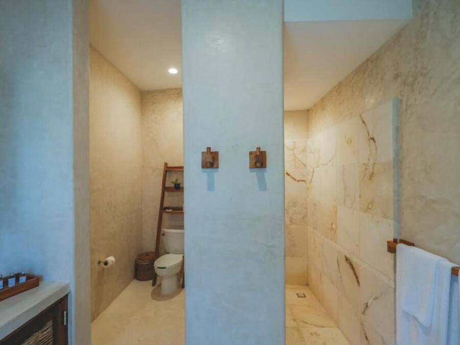 Un baño con pared de mármol, inodoro, lavamanos y perchero.