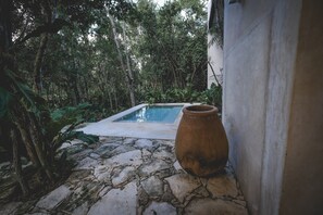 A stone-paved area with a small pool and a large terracotta pot.