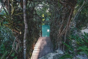 A wooden pathway leading to a turquoise door surrounded by dense foliage. - Wakax Hacienda - Cenote & Boutique Hotel - Small Luxury Hotels of the World (Tulum)