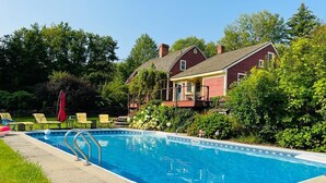 A swimming pool with a red house in the background. - A cozy home nestled in the Green Mountains of Vermont! (Pownal)