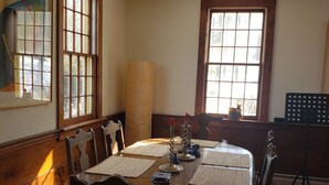 A dining room with a wooden table, chairs, and a window with a view of trees. - A cozy home nestled in the Green Mountains of Vermont! (Pownal)