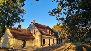 Une rangée de maisons traditionnelles aux toits inclinés et aux cheminées, entourées d’arbres et bordées d’un chemin de gravier.