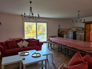 A living room with a red sofa, a white coffee table, and a dining table with a red and white checkered tablecloth.