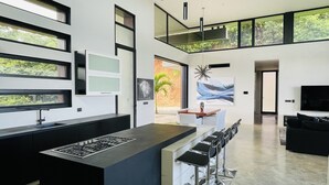 Eine moderne Küche mit Kochinsel, Barhocker und Essbereich mit Tisch und Stühlen.