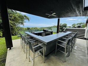 An outdoor bar area with a concrete countertop and metal chairs, overlooking a lush landscape. - Breathtaking luxury meets nature
With amazing Ocean and Jungle view  (San Juanillo)