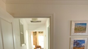 A hallway with a patterned rug, a door on the left, and framed pictures on the wall. - Swede Hill Suite (Moscow)