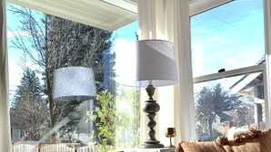 A bedroom with a bed, a table with a lamp, wicker baskets, and a view of the outside. - Swede Hill Suite (Moscow)